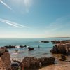 Spiaggia rocciosa con bagnanti e ombrelloni.