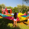 Bambini giocano all'aperto con un telo colorato.
