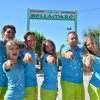Un gruppo di persone sorride davanti al cartello di un campeggio.