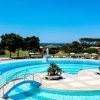 Una grande piscina all'aperto con una fontana centrale, circondata da alberi e sedie a sdraio.