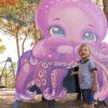 Bambino accanto a un cartonato di polpo viola sorridente.