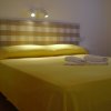Letto matrimoniale con copriletto giallo e asciugamani arrotolati.