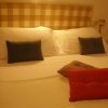 Letto matrimoniale con cuscini blu e rossi, testata a quadri beige.