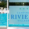 Piscina con persone che nuotano, visibile il cartello 