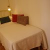 Letto singolo con tre cuscini colorati su copriletto bianco, sotto una luce.
