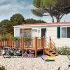Casa mobile con veranda e biciclette, circondata da alberi.