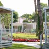 Bungalow moderni immersi in un giardino fiorito con vialetti erbosi e alberi alti.