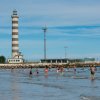 Persone in acqua vicino a un faro a strisce.