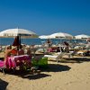 Spiaggia con lettini e ombrelloni bianchi.