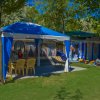 Una tenda blu con sedie gialle su erba.