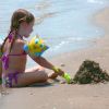 Bambina con braccioli gioca con la sabbia vicino al mare.
